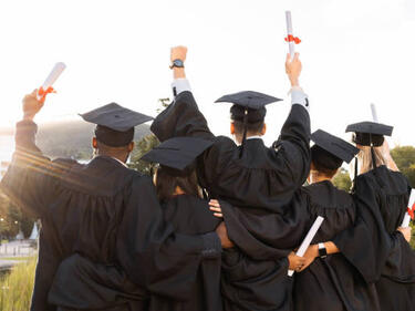 a group of graduates with their arms raised in happiness